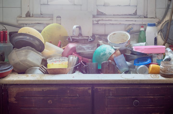 Image: A kitchen bench and sink covered in piles of dirty dishes